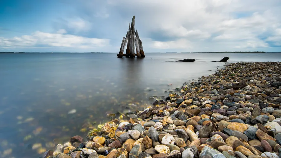 Steine am Ufer und Holzpfähle im Wasser der Ostsee